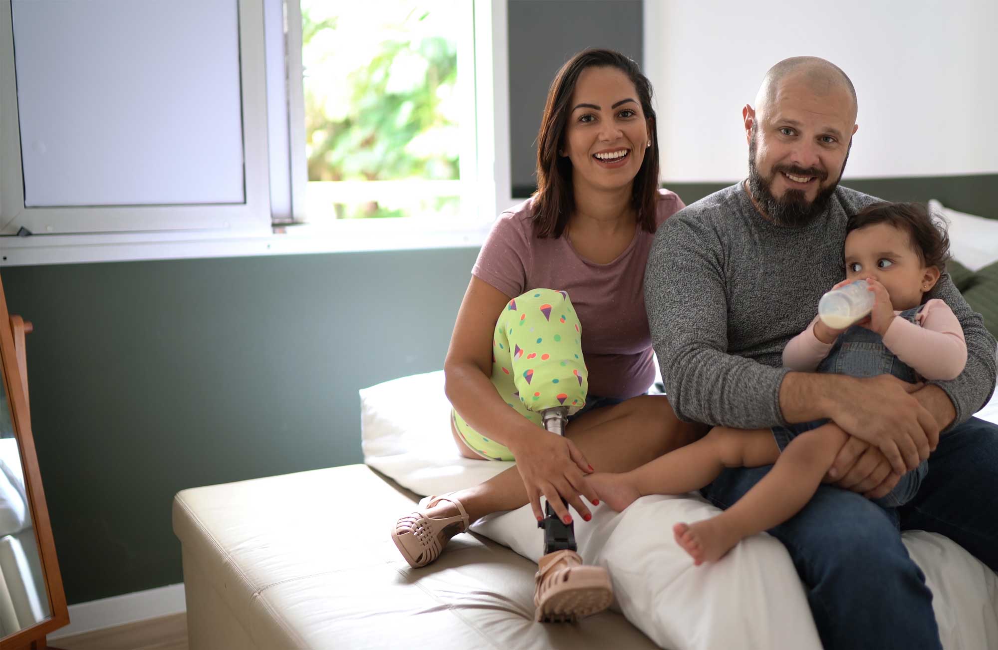 a photo of a family: a mom who has a prosthetic leg, her husband and their infant